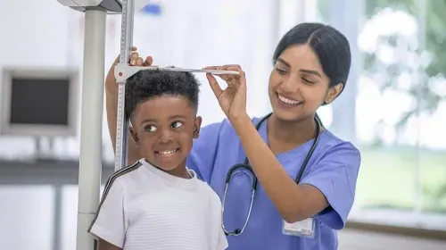 Medical assistant checking the height of pediatric patient